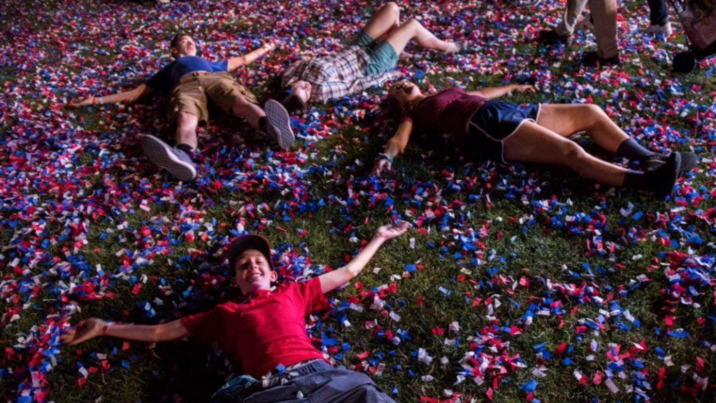 People lying on confetti-covered grass (© Nicholas Pfosi/The Boston Globe/Getty Images)